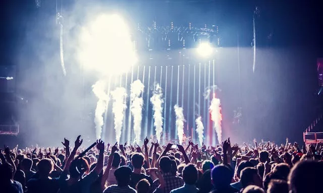 Crowded concert audience with raised hands and pyrotechnics on stage during HARDY live show in Calgary.