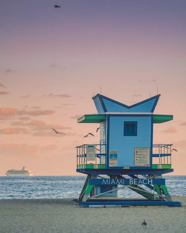 Longines Global Champions Tour — sunrise-lit Miami Beach lifeguard tower with seagulls overhead.