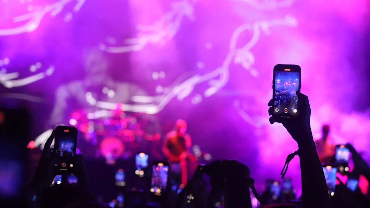 Crowd at a purple-lit BTS concert in Toronto, many fans hold up phones recording the stage and lights.
