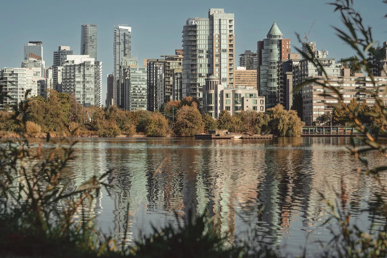 Vancouver skyline and waterfront reflected in calm water beside text promoting the Vancouver Cherry Blossom Festival.