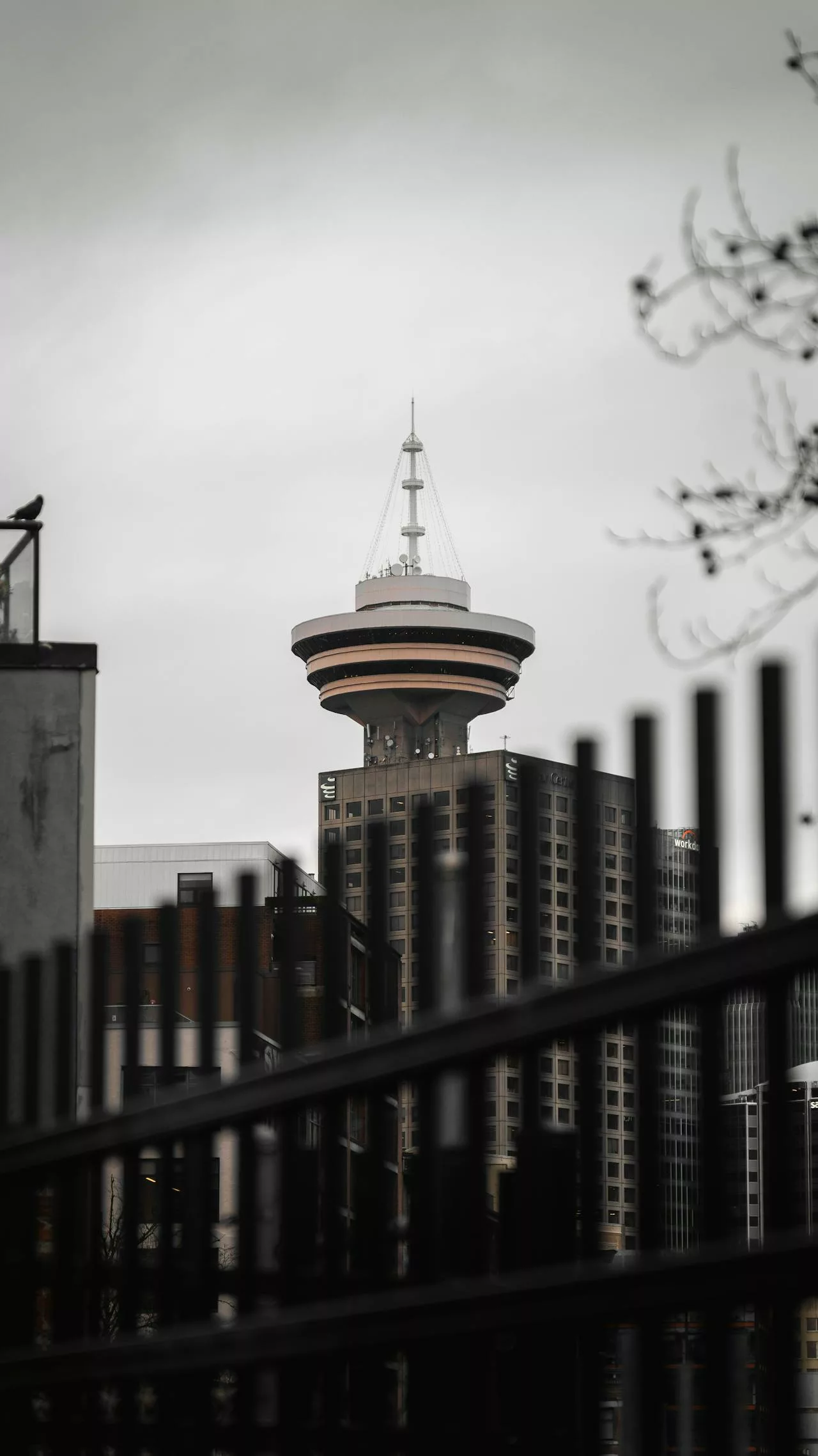 Vancouver Harbour Centre tower framed by buildings and fence; mention Vancouver car rental services.