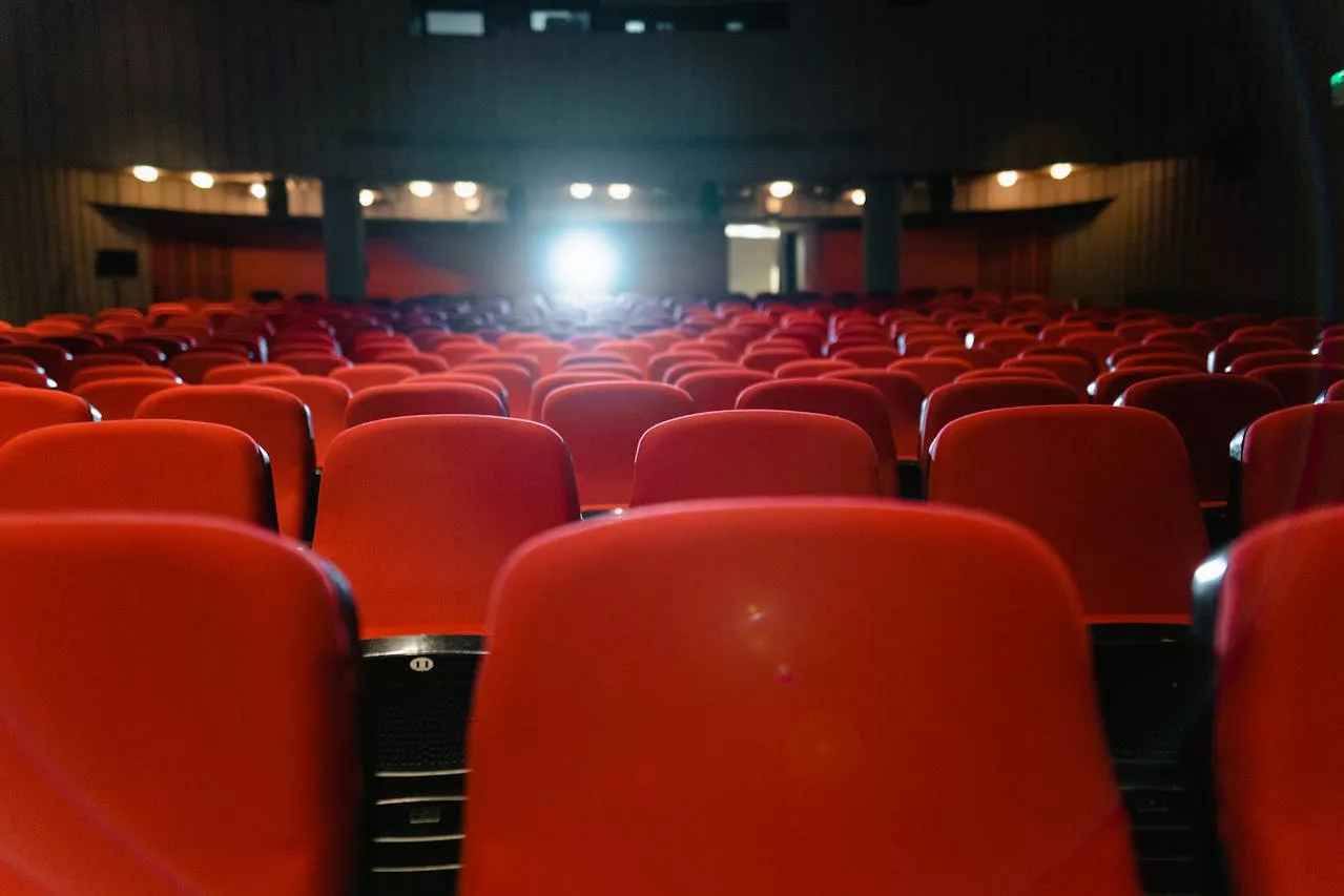 Miami Film Festival — empty theater rows with red seats and a projector beam lighting the screen.