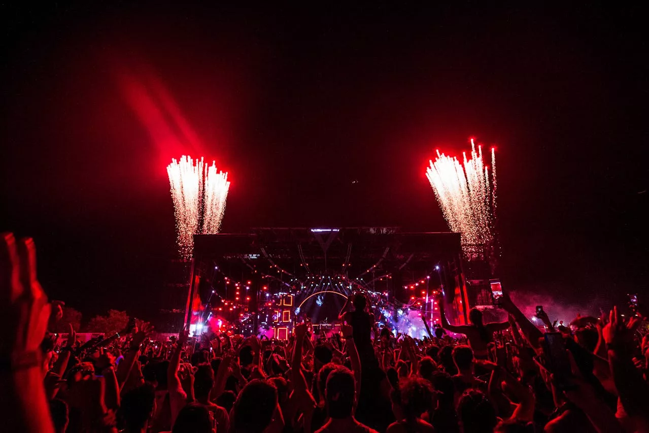 Crowd enjoying Lady Gaga Mayhem Ball Tour concert with fireworks display.