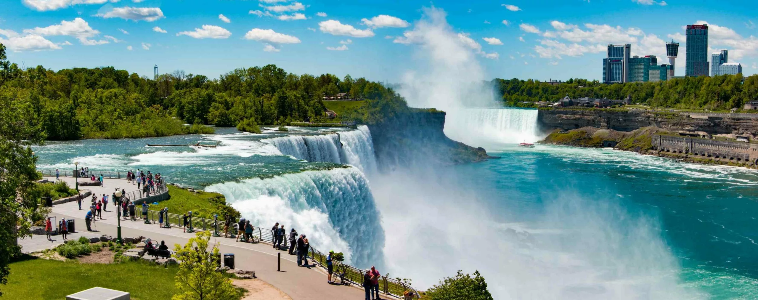 Beautiful panoramic view of Niagara Falls with turquoise water, tourists, and skyline scenery during a Toronto to Niagara Falls travel experience.