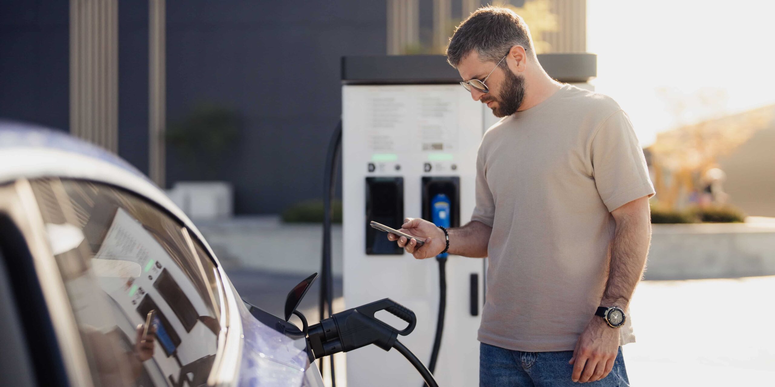 A white electric car charging at a downtown Vancouver parking station, representing EV car rental Vancouver options in 2026