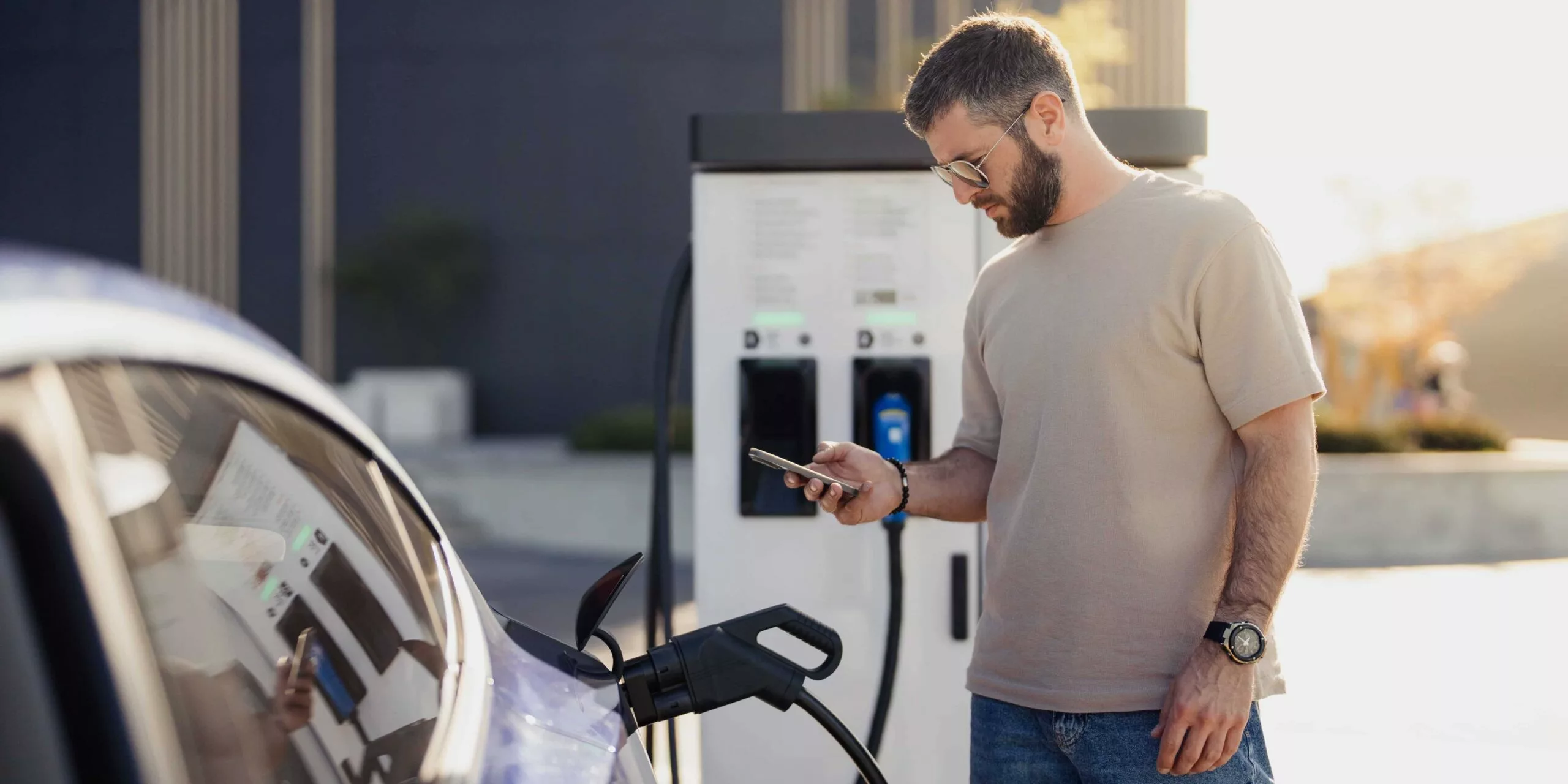 A white electric car charging at a downtown Vancouver parking station, representing EV car rental Vancouver options in 2026