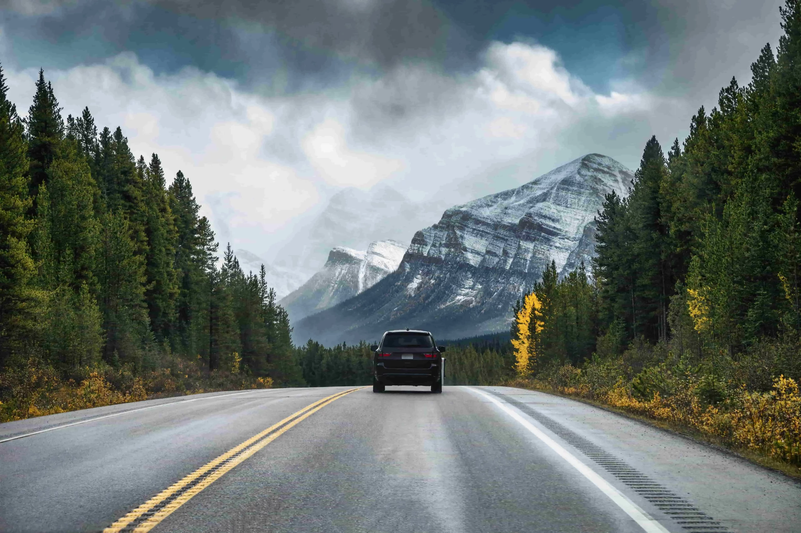 SUV driving through the Canadian Rockies during fall